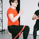 Personal trainer guiding a woman with resistance band exercise in a gym setting.